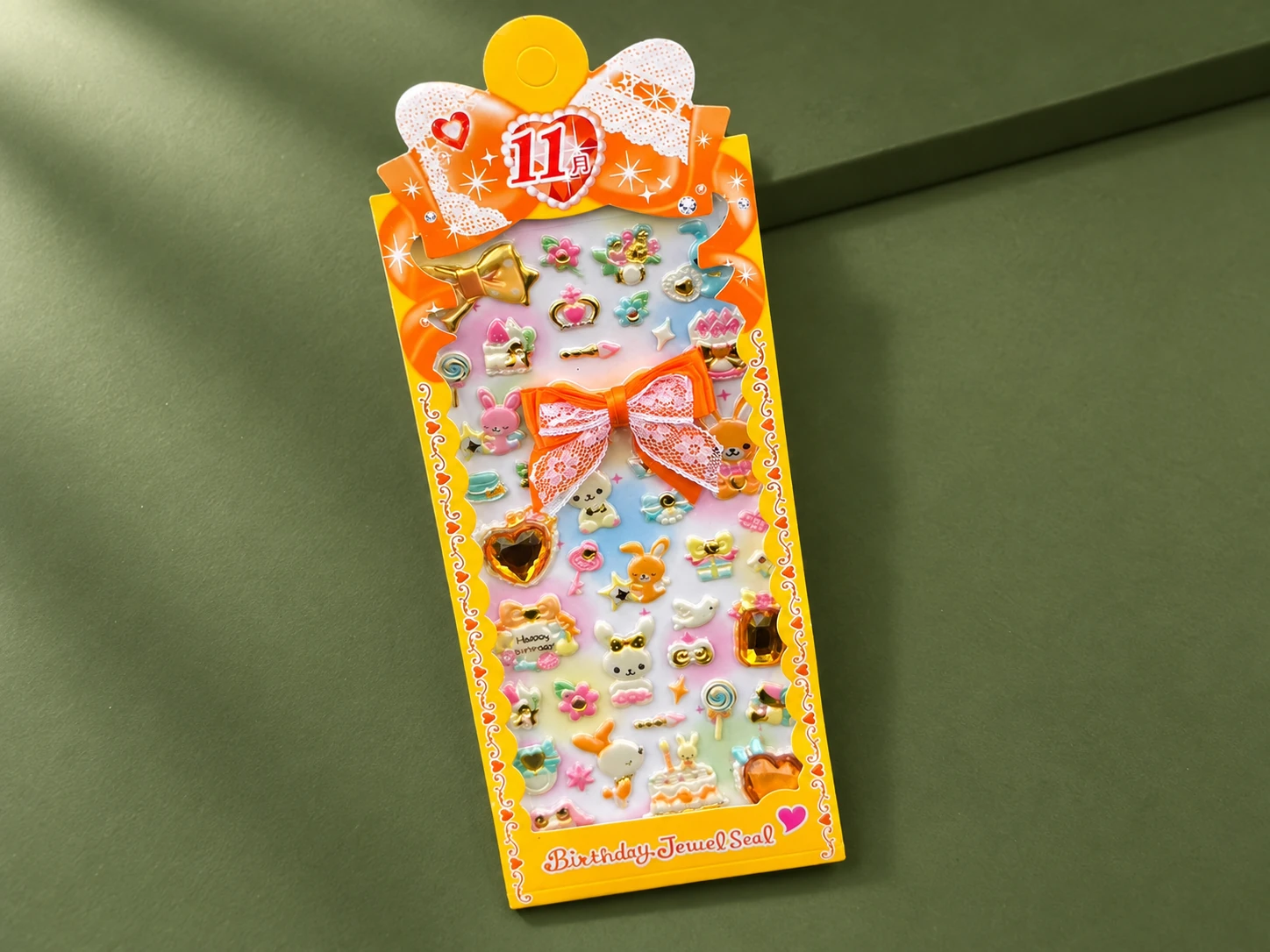 Birthday-themed puffy sticker sheet in orange bow-shaped packaging
